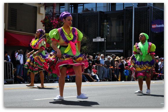 The SF Carnaval Parade with three dancers in the street.