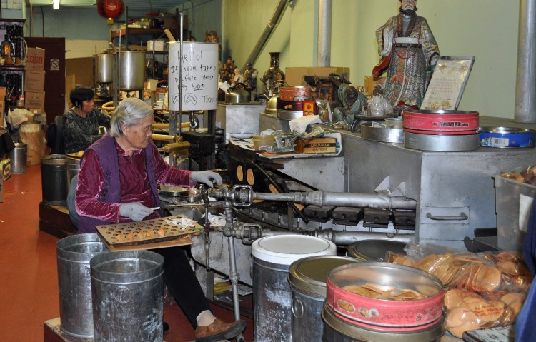 Two women working away in the Golden Gate Fortune Cookie Factory in Chinatown.