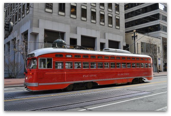 A red San Francisco street car riding down Market Street